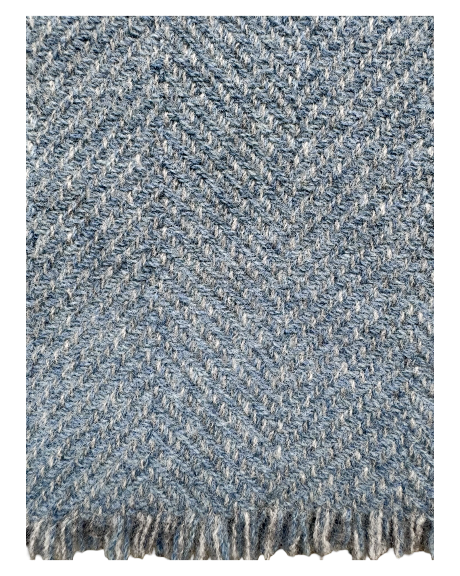 A close-up of woven wool textile with a blue grey and white herringbone pattern and fringed edge.