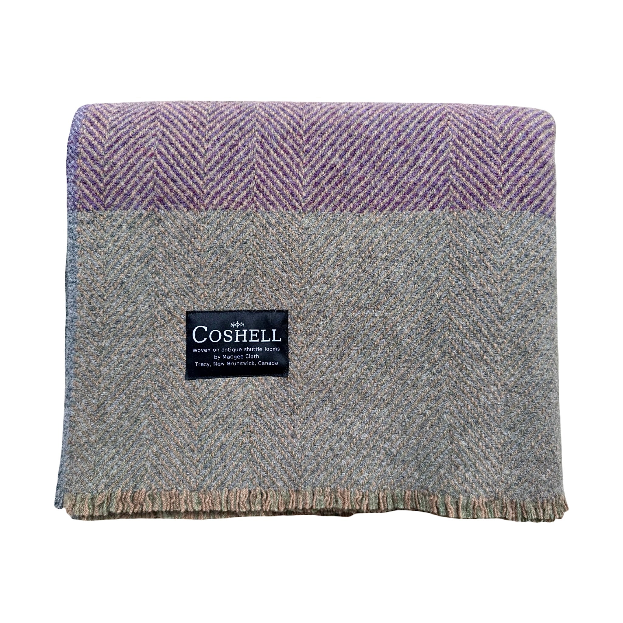 A folded herringbone wool throw blanket by Coshell, featuring a lavender-purple and gray patterned top section and a heathered gray lower section with a black brand label.