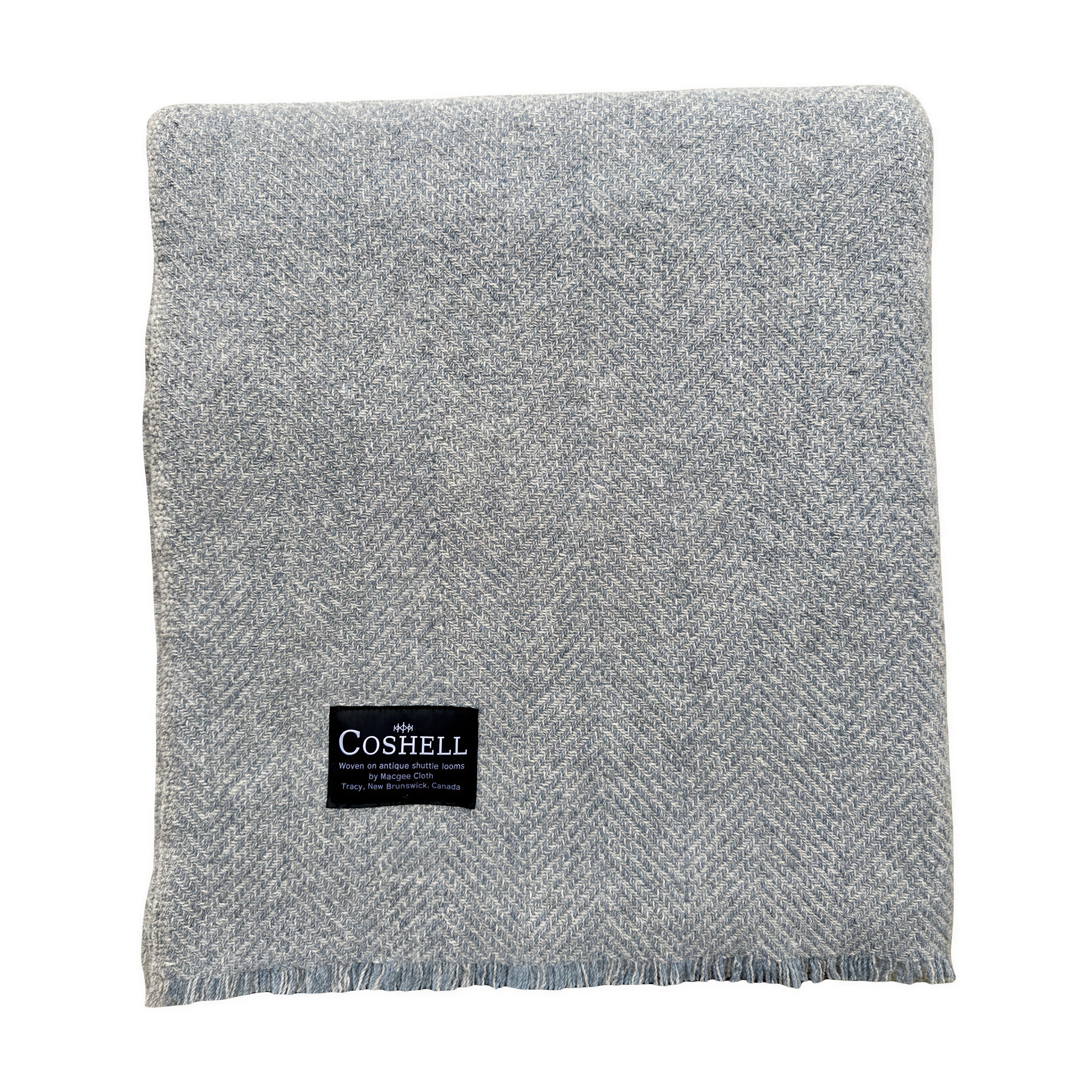 A folded light blue with grey herringbone woven blanket with a black Coshell brand label on the front